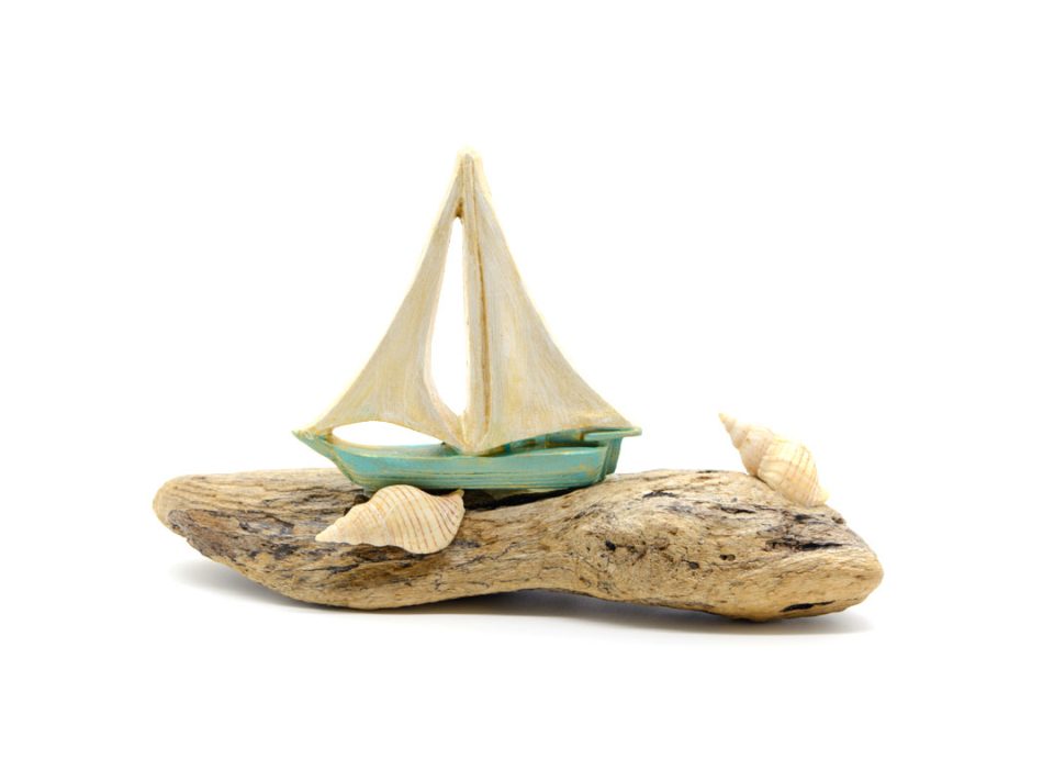 Handmade boat, bright green with white sails, in sea wood