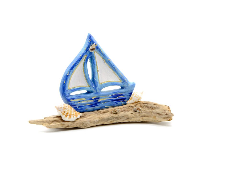 Handmade boat, light blue, on sea wood