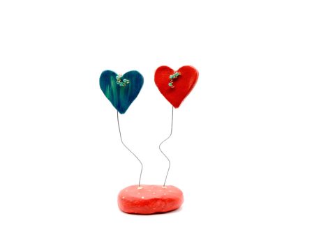 Handmade hearts from clay, red blue on a clay base