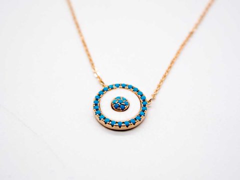 Steel necklace in rose gold with round white element with turquoise stones.