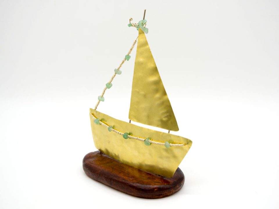 bronze boat in gold color with a sail on a clay base.